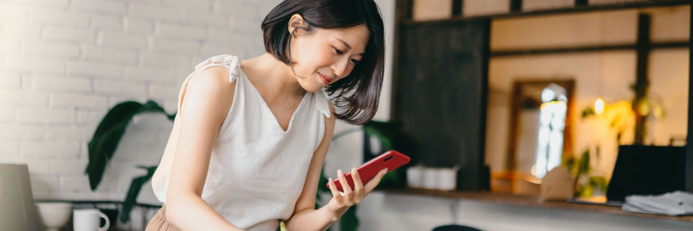 woman holding a smartphone while unboxing fresh goods