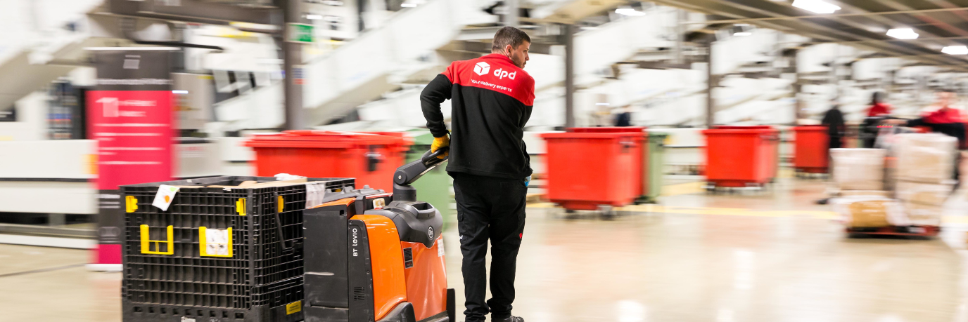 Man dragging a pile of parcels inside of a warehouse