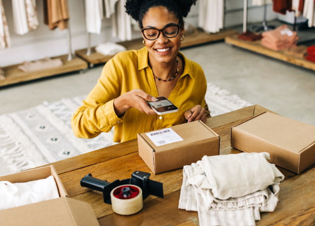 Woman preparing a parcel for delivery while scanning the label with her phone