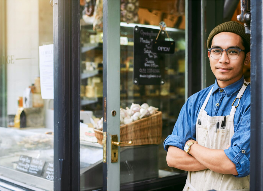 Cook wearing an apron leaning at the door of their shop