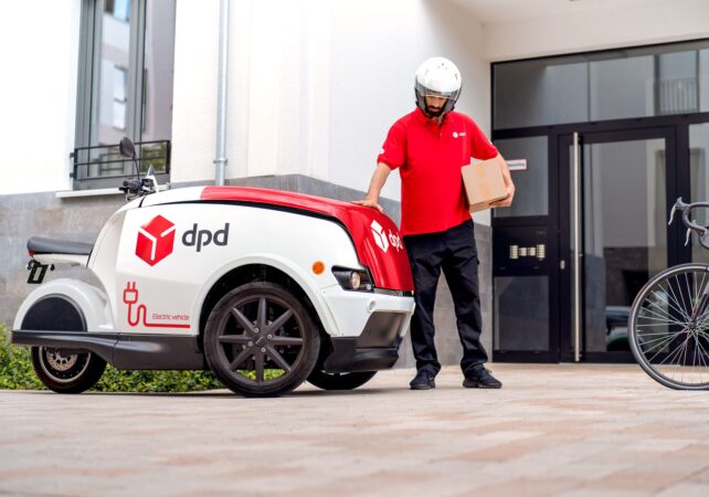 DPD Driver holding a parcel beside a delivery robot