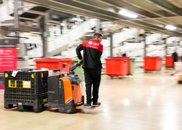 DPD employee carrying parcels in a warehouse